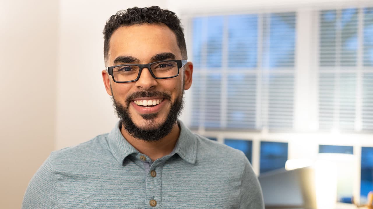 Sunjay Armstead smiling big in a jade green collared shirt